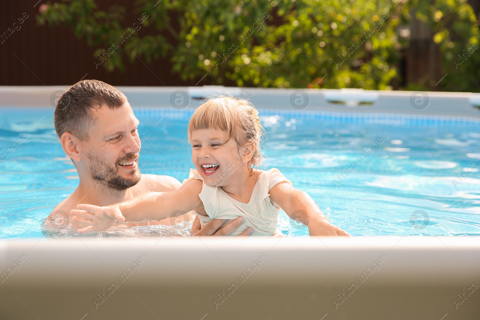 Photo of Happy daughter and her father resting in swimming pool