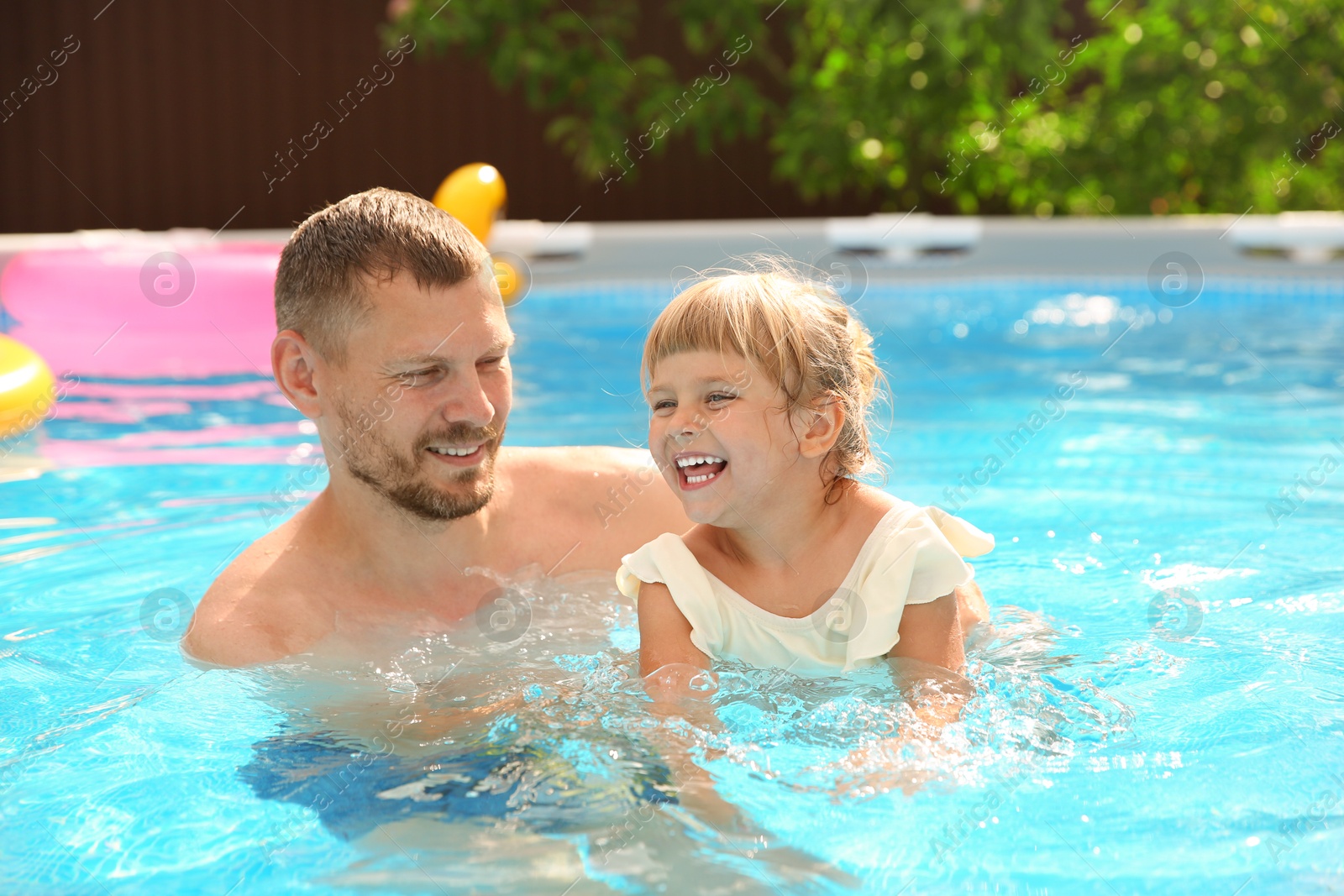 Photo of Happy daughter and her father having fun in swimming pool