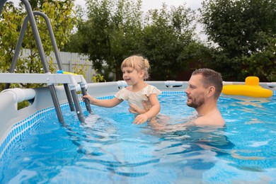 Happy daughter and her father having fun in swimming pool