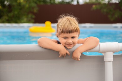 Photo of Little girl resting in swimming pool outdoors, selective focus