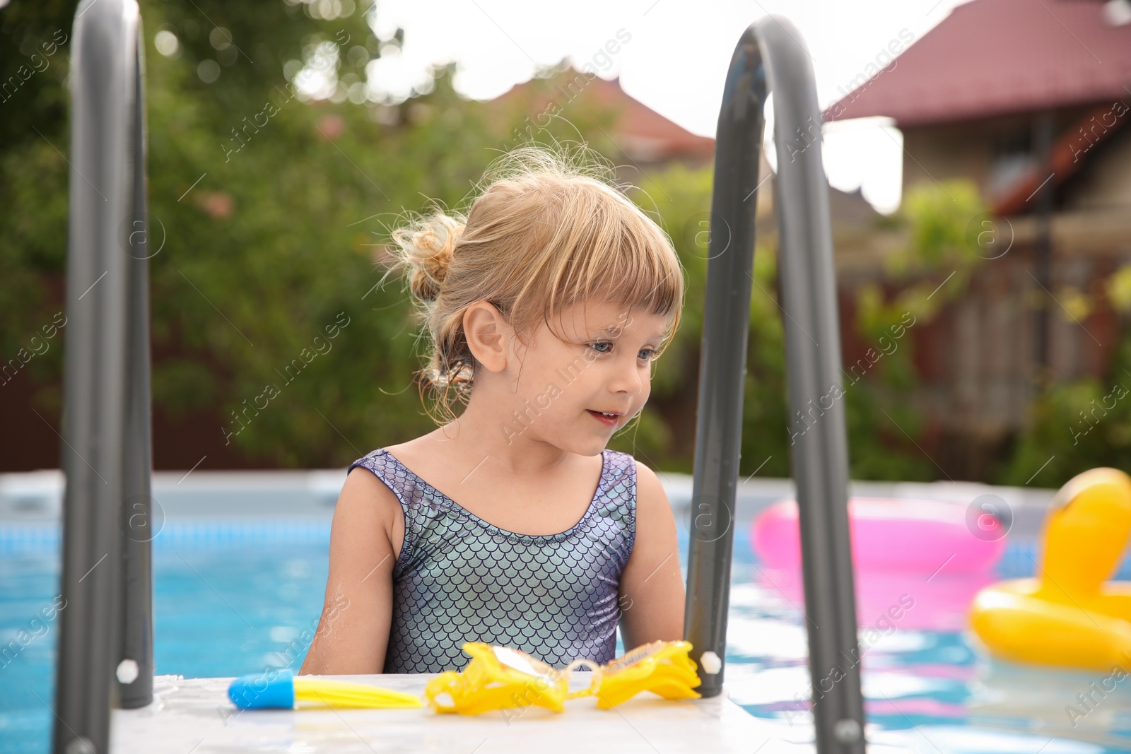 Photo of Little girl resting in swimming pool outdoors