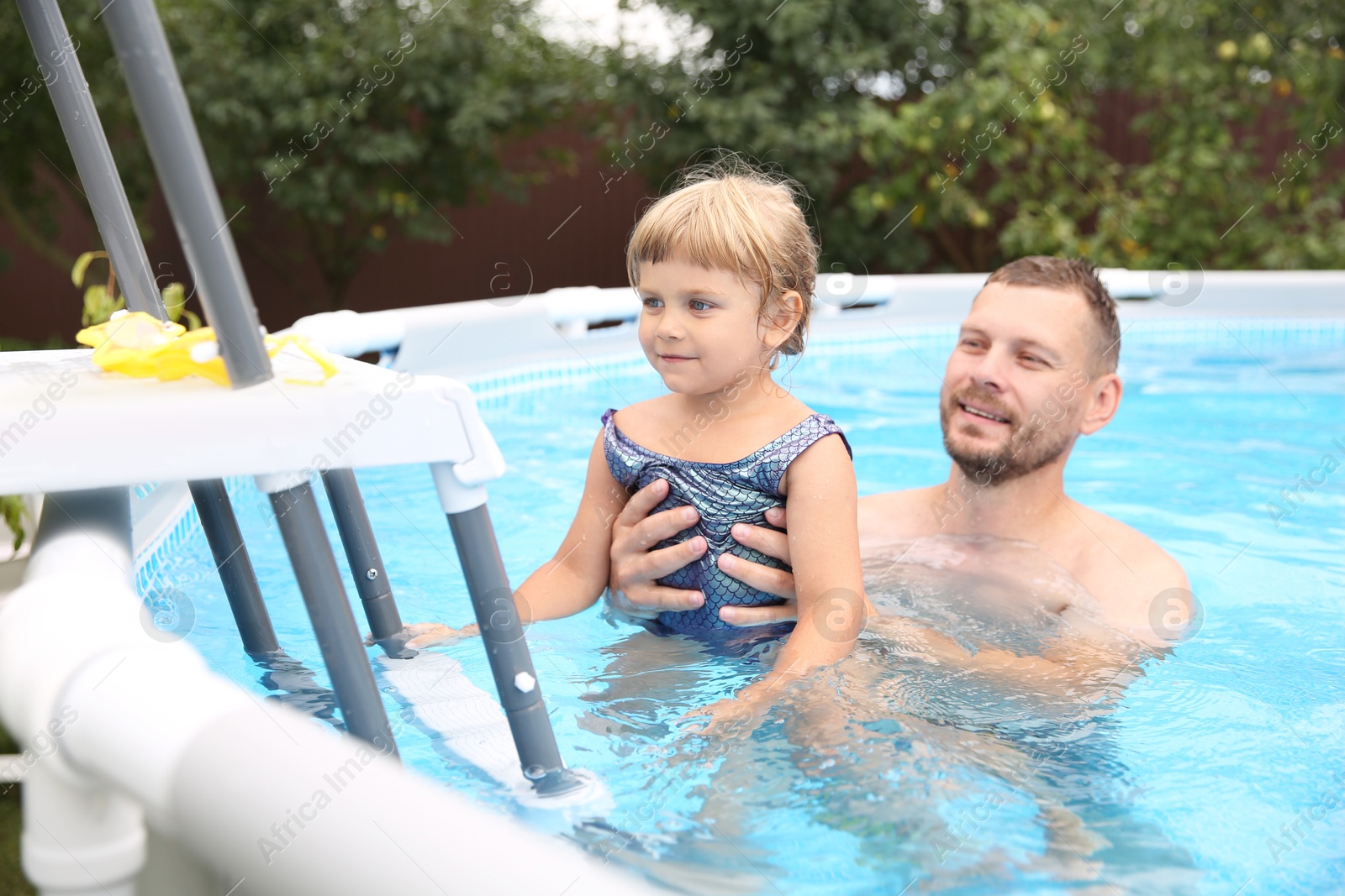 Photo of Happy daughter and her father having fun in swimming pool