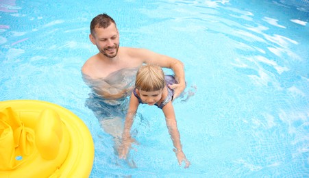 Daughter and her father swimming in pool