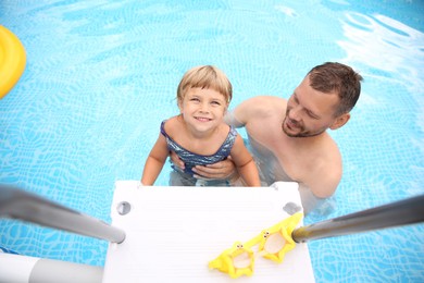 Photo of Happy daughter and her father near ladder in swimming pool, above view