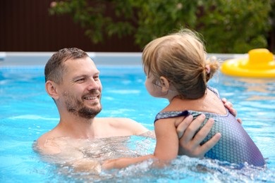 Happy father having fun with his daughter in swimming pool