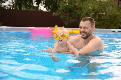 Photo of Happy father having fun with his son in swimming pool