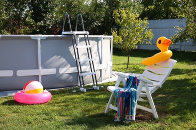 Photo of Above ground swimming pool, folding chair, towel, inflatable rings and ball in backyard