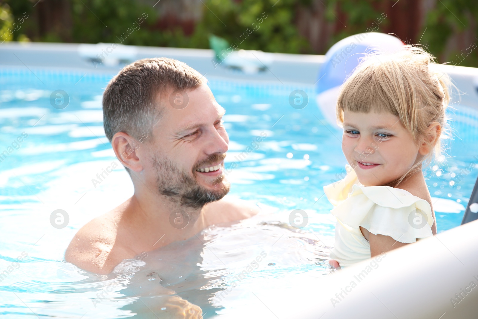 Photo of Happy father having fun with his daughter in swimming pool