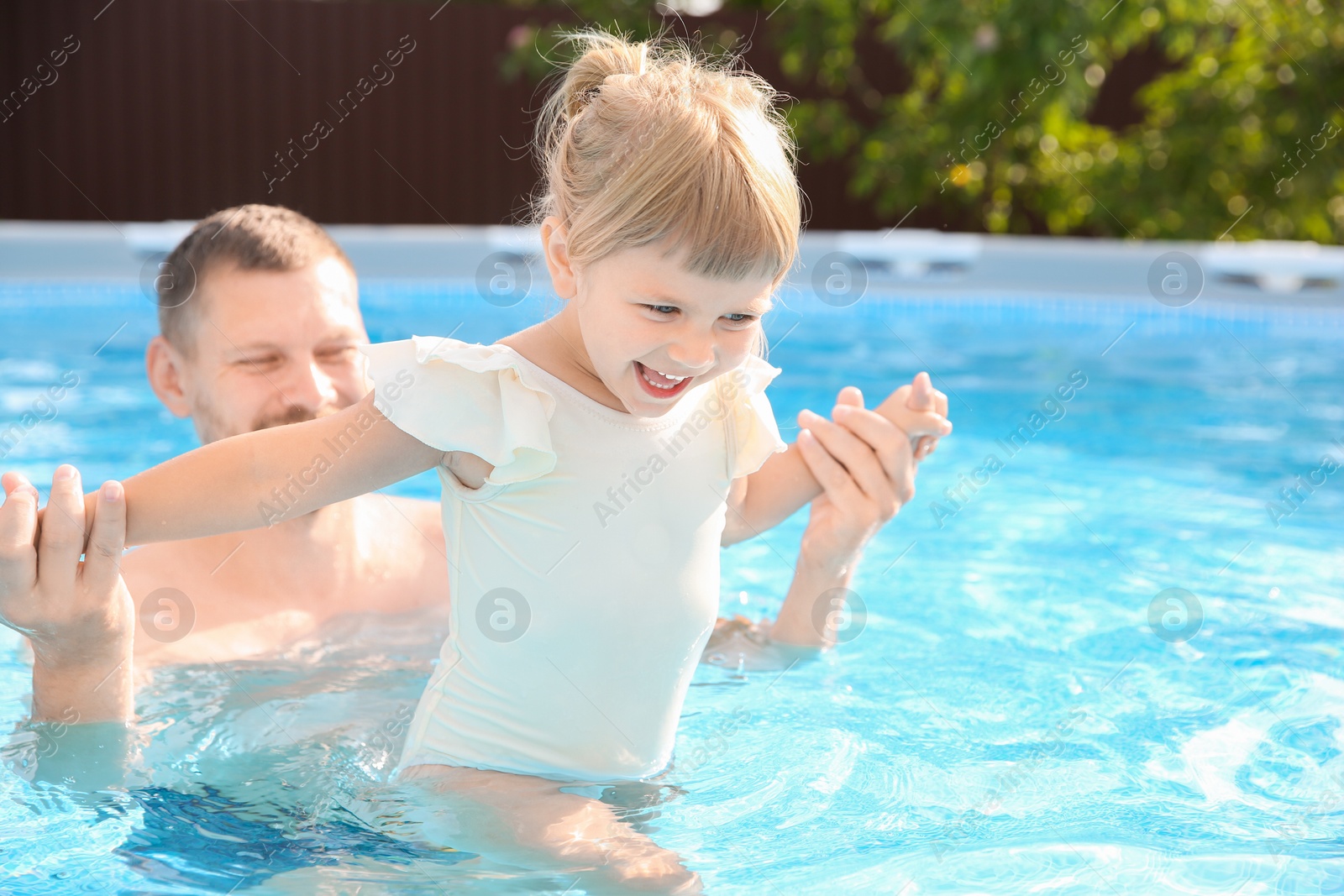 Photo of Happy father having fun with his daughter in swimming pool, space for text