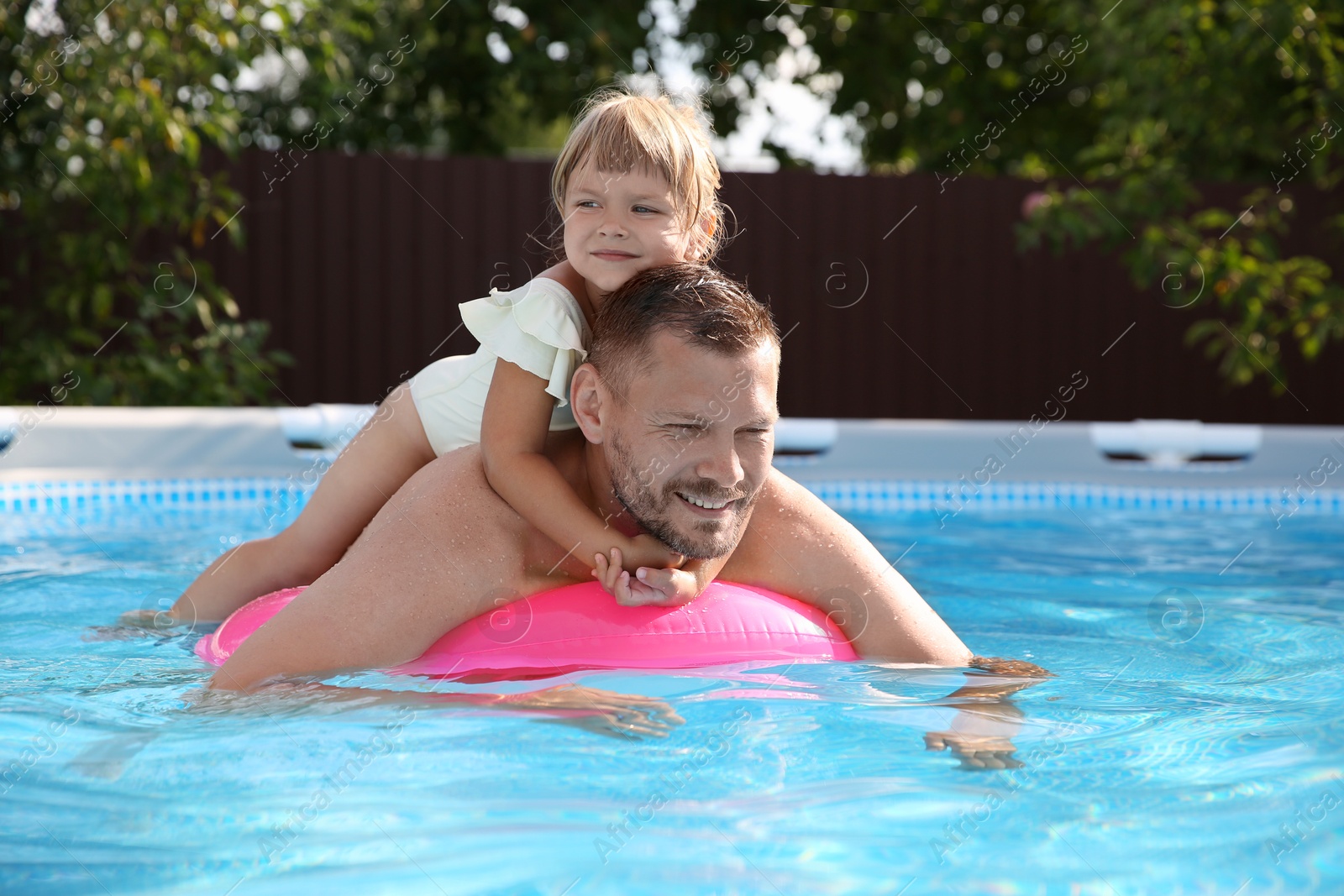 Photo of Happy father having fun with his daughter in swimming pool