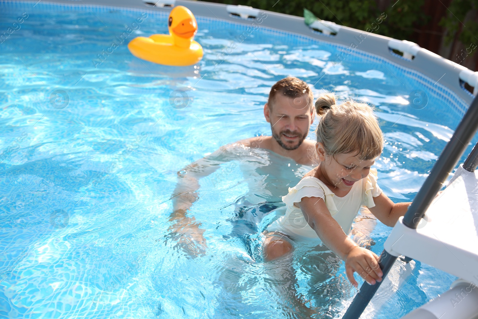 Photo of Little girl getting out of swimming pool by ladder outdoors, space for text