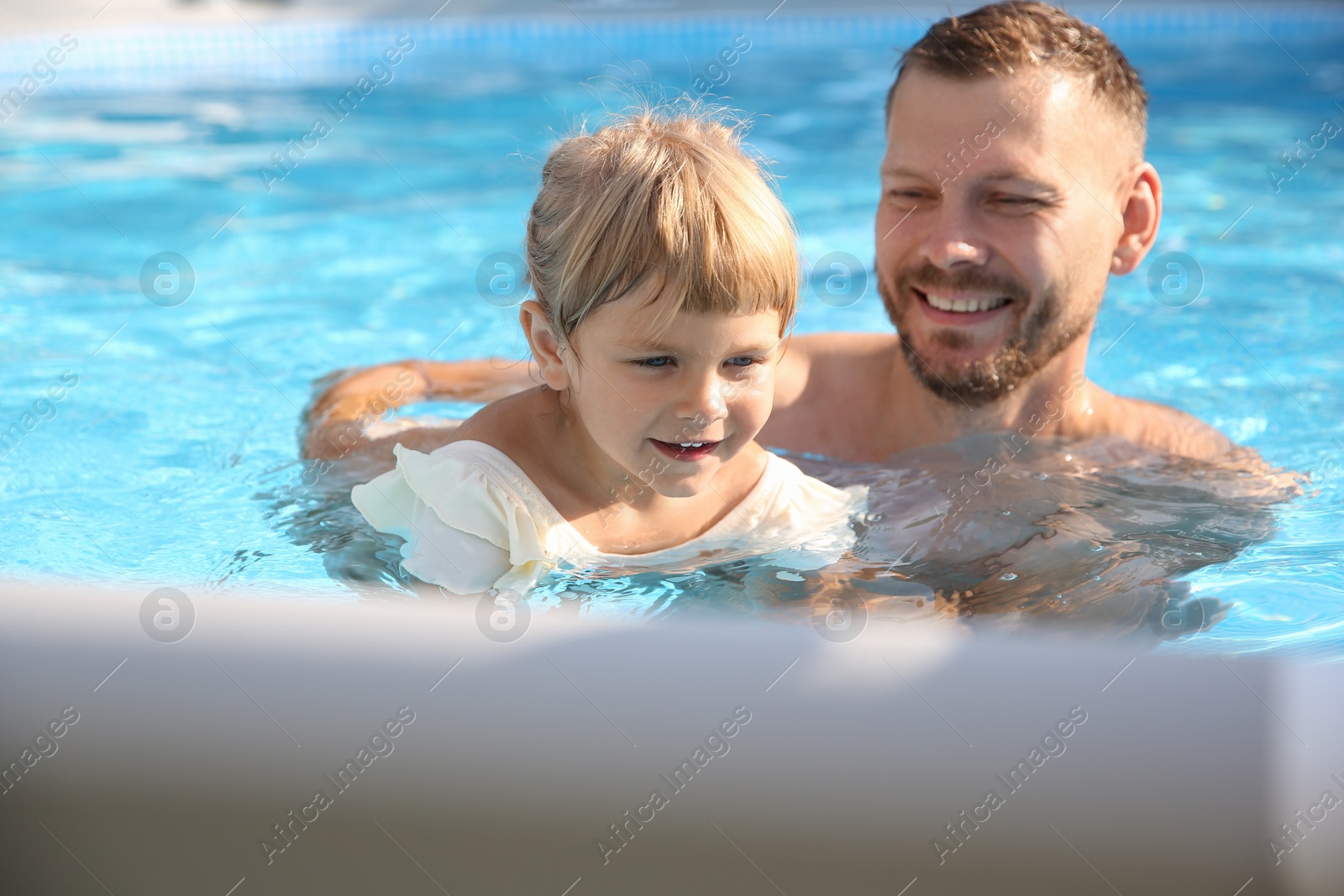 Photo of Little girl getting out of swimming pool by ladder outdoors