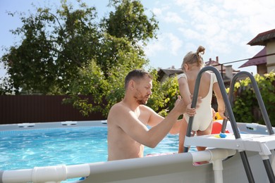 Photo of Father and her daughter resting in swimming pool outdoors