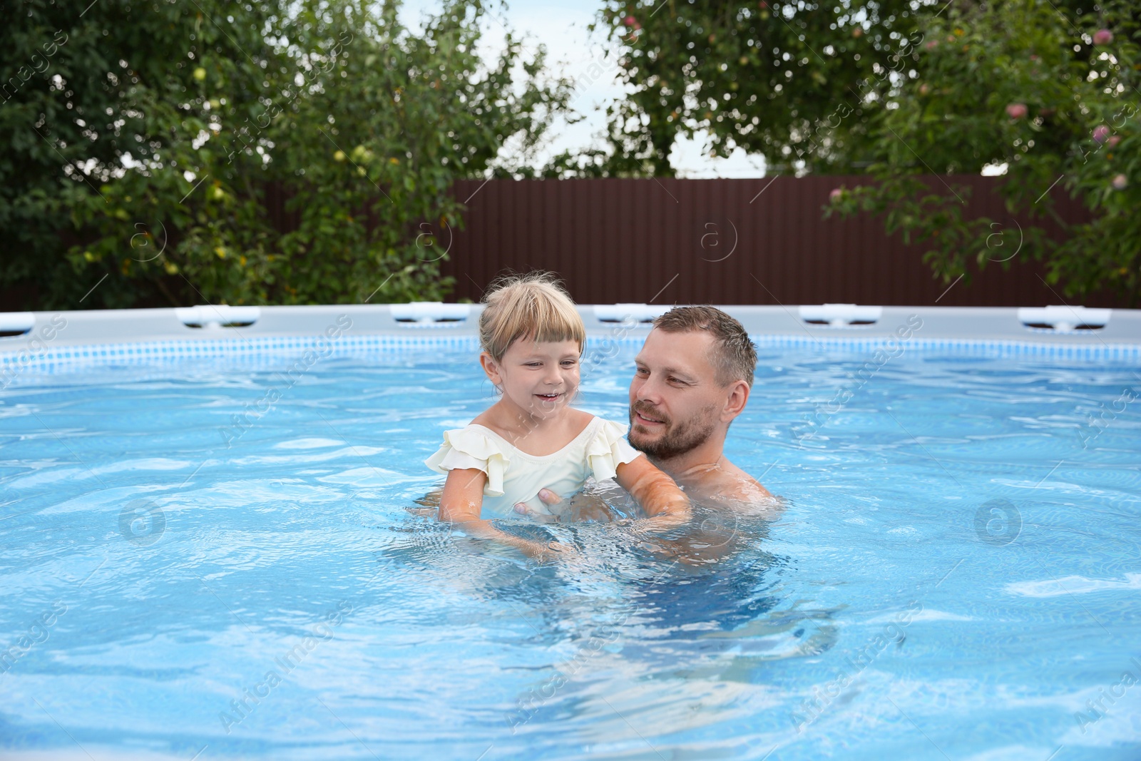 Photo of Happy father having fun with his daughter in swimming pool