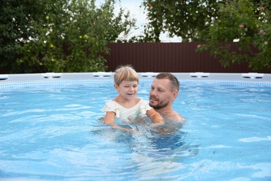 Photo of Happy father having fun with his daughter in swimming pool