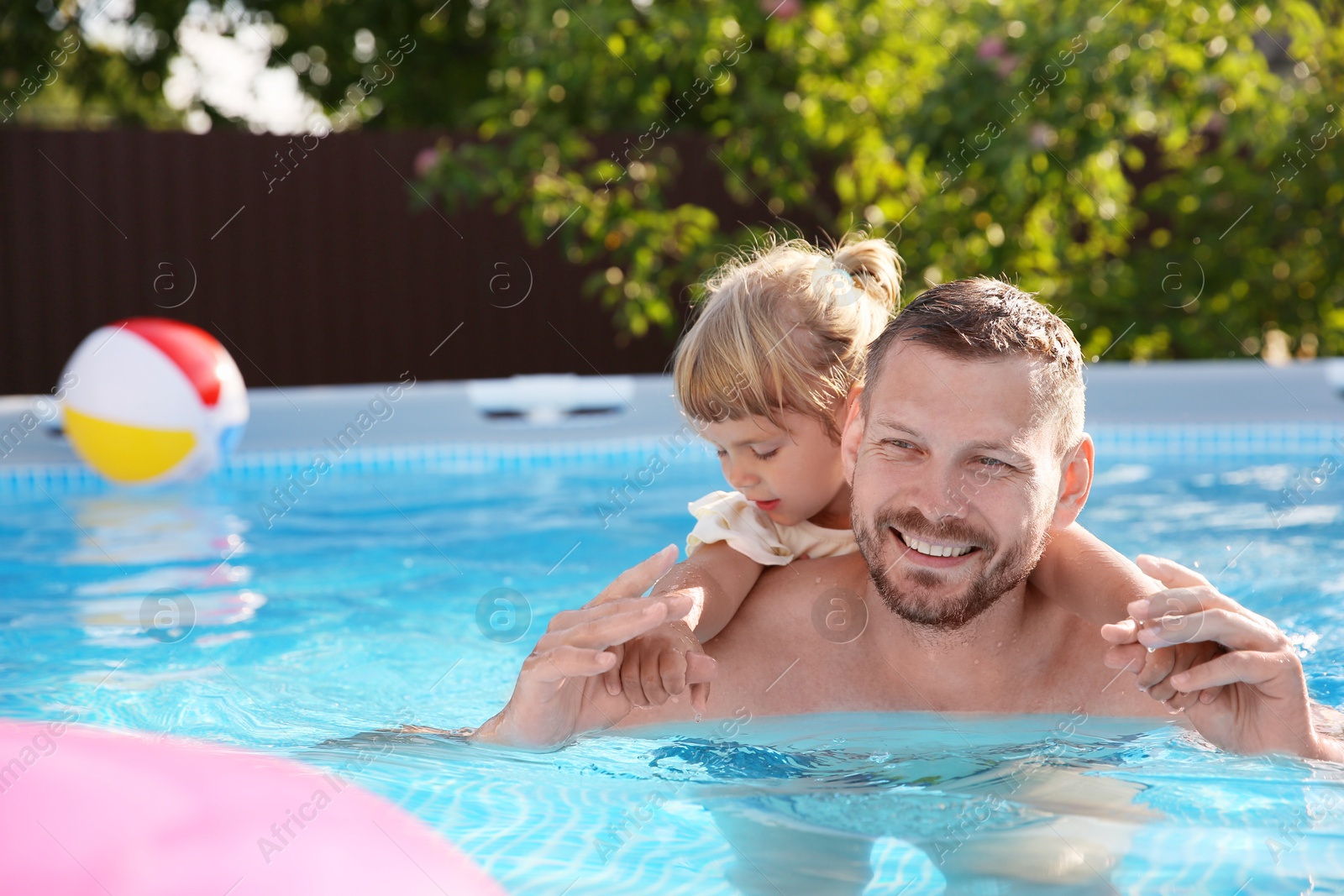 Photo of Happy father having fun with his daughter in swimming pool, space for text