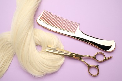 Photo of Blonde hair strand, comb and professional scissors on violet background, top view