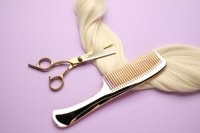 Photo of Blonde hair strand, comb and professional scissors on violet background, top view