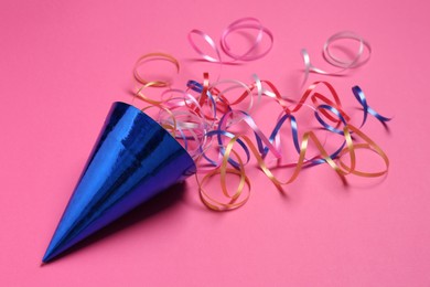 Photo of Blue party hat with streamers on bright pink background