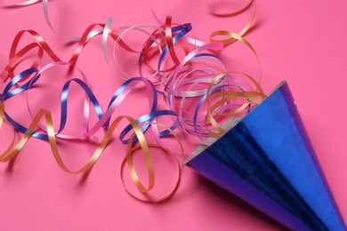 Blue party hat with streamers on bright pink background