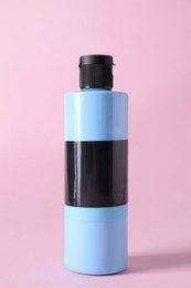 Light blue acrylic paint in bottle on pink background