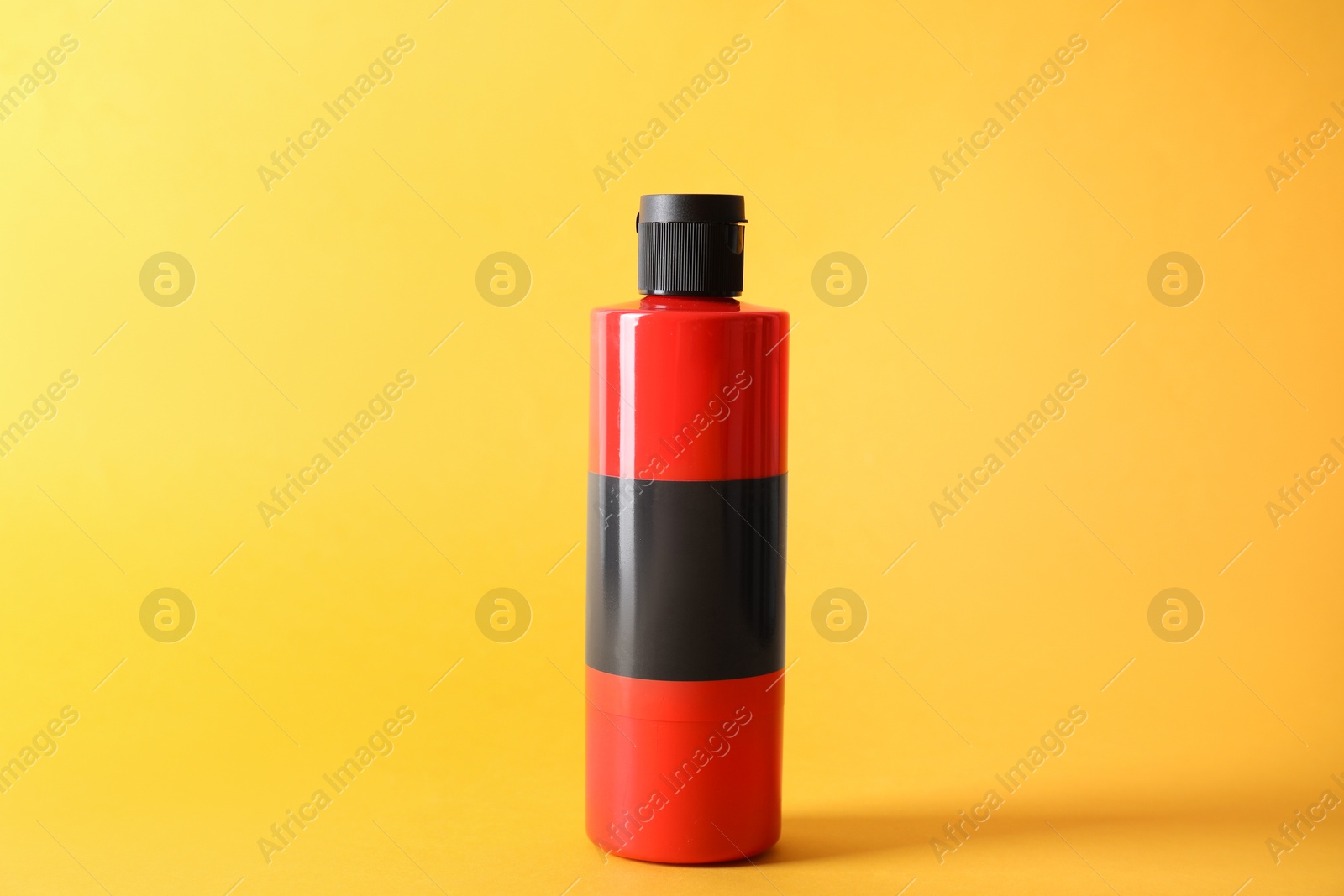 Photo of Red acrylic paint in bottle on orange background