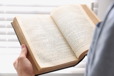 Man with Bible indoors, closeup. Christian faith