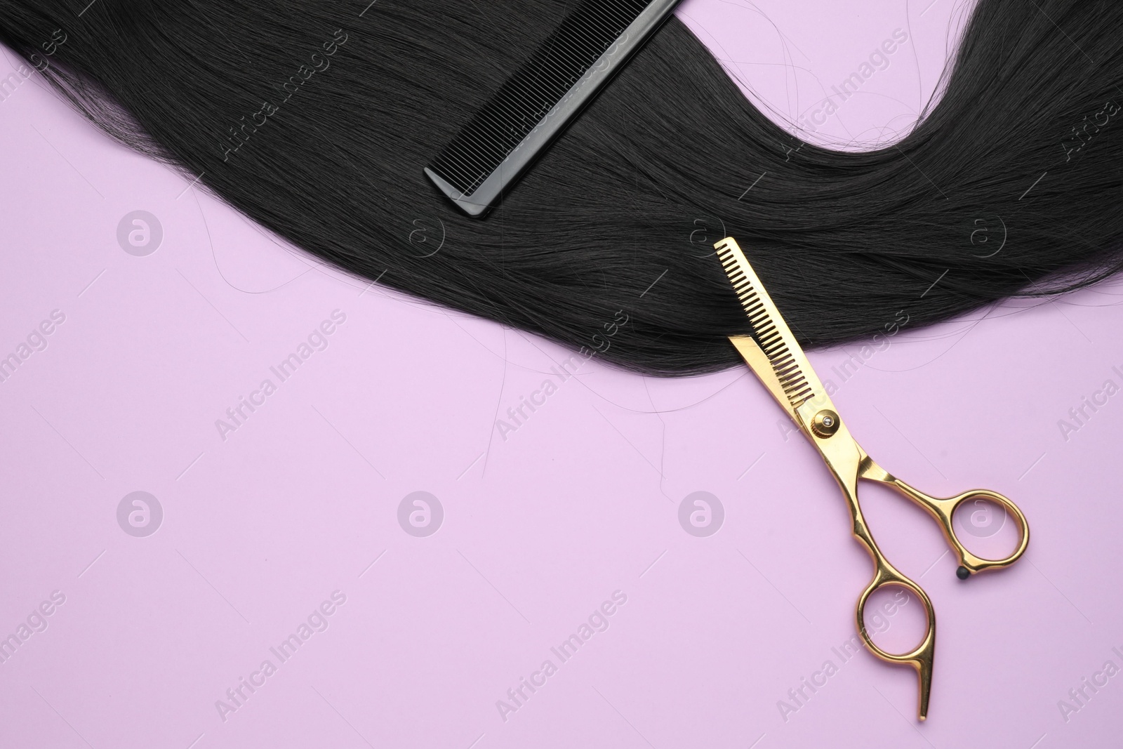 Photo of Black hair strand, comb and professional scissors on violet background, top view. Space for text