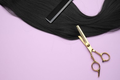 Photo of Black hair strand, comb and professional scissors on violet background, top view. Space for text