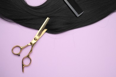 Photo of Black hair strand, comb and professional scissors on violet background, top view. Space for text