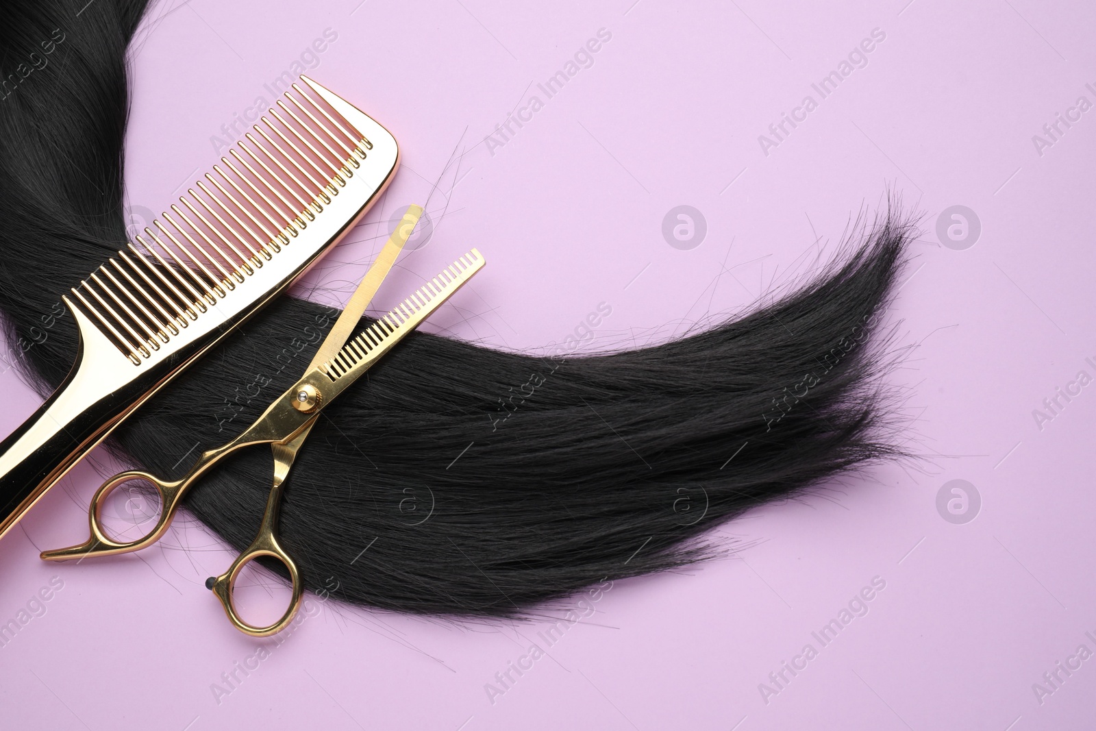 Photo of Black hair strand, comb and professional scissors on violet background, top view