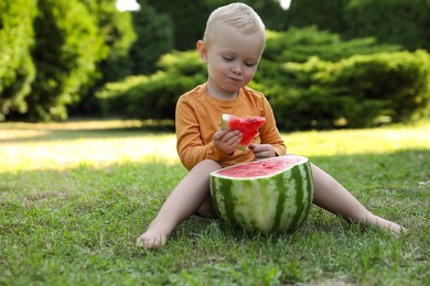 Photo of Cute little baby eating juicy watermelon on green grass outdoors