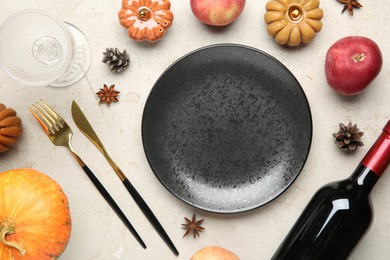 Stylish place setting, bottle of wine and autumn decor on grey textured table