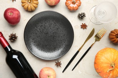 Photo of Stylish place setting, bottle of wine and autumn decor on grey textured table