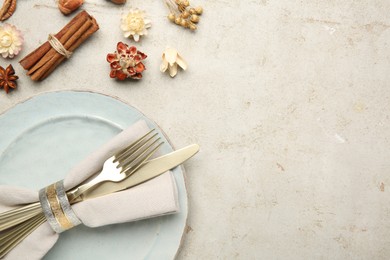 Photo of Stylish place setting, cinnamon and dry flowers on grey textured table. Space for text