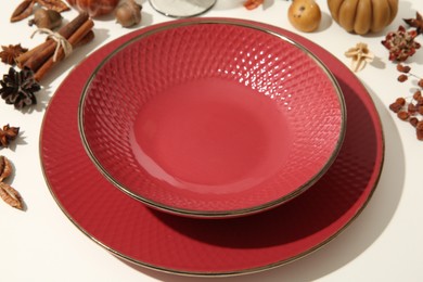 Photo of Red plate, bowl and autumn decor on white background, closeup