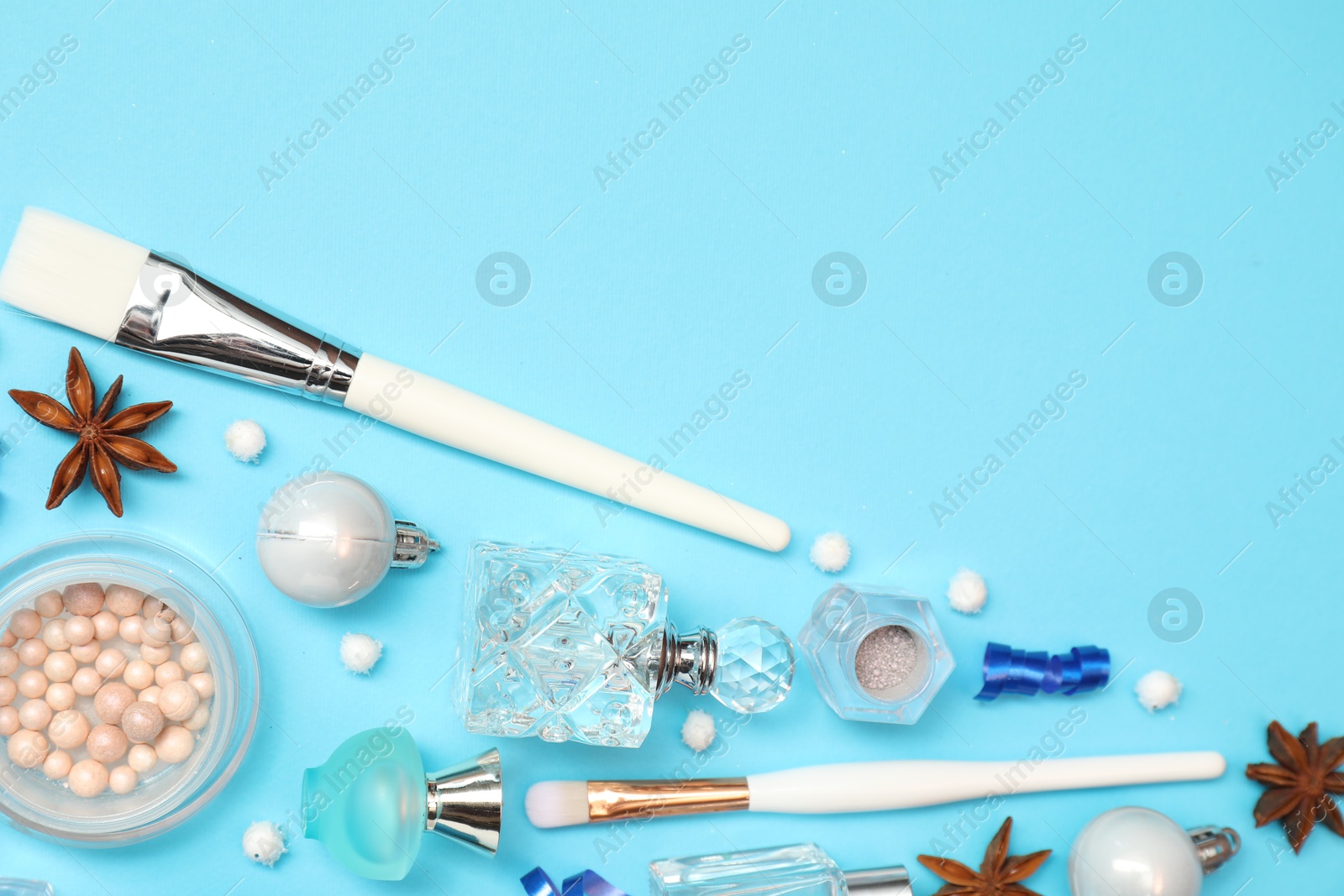 Photo of Perfume bottles and makeup products on light blue background, flat lay. Space for text