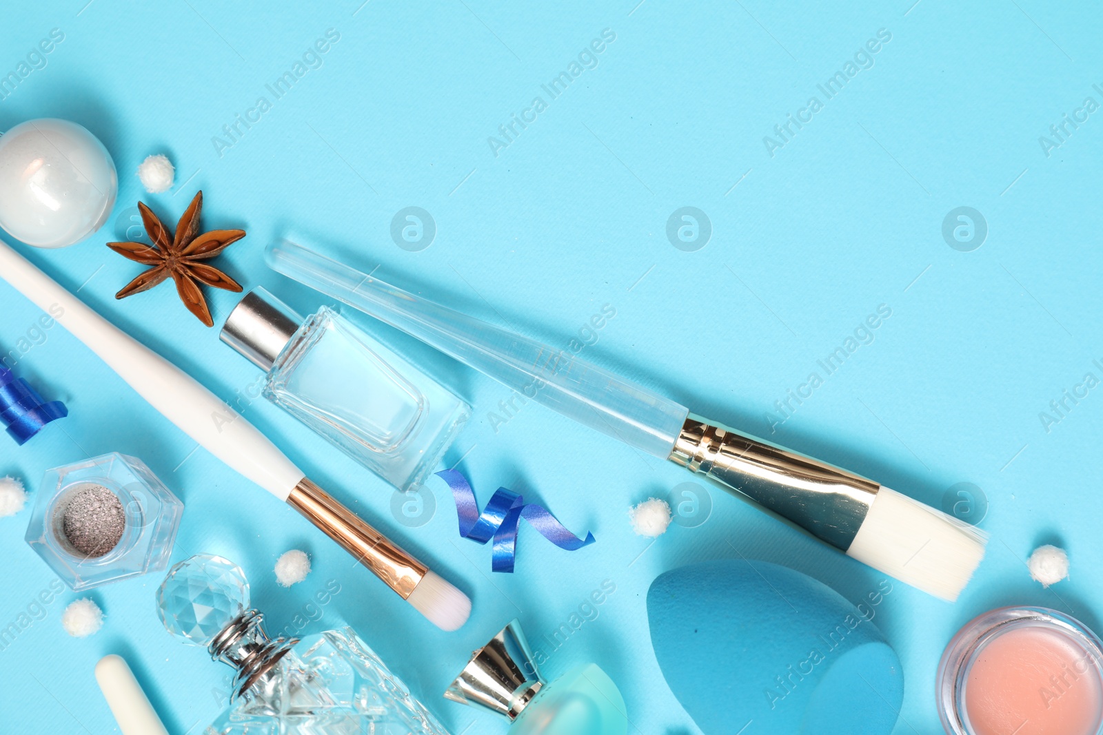 Photo of Perfume bottles and makeup products on light blue background, flat lay. Space for text