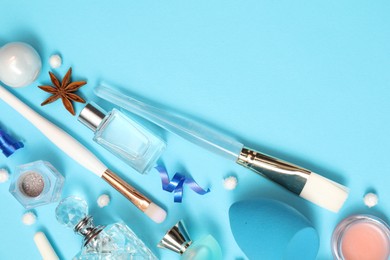 Perfume bottles and makeup products on light blue background, flat lay. Space for text