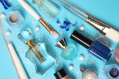 Photo of Perfume bottles and makeup products on light blue background, flat lay