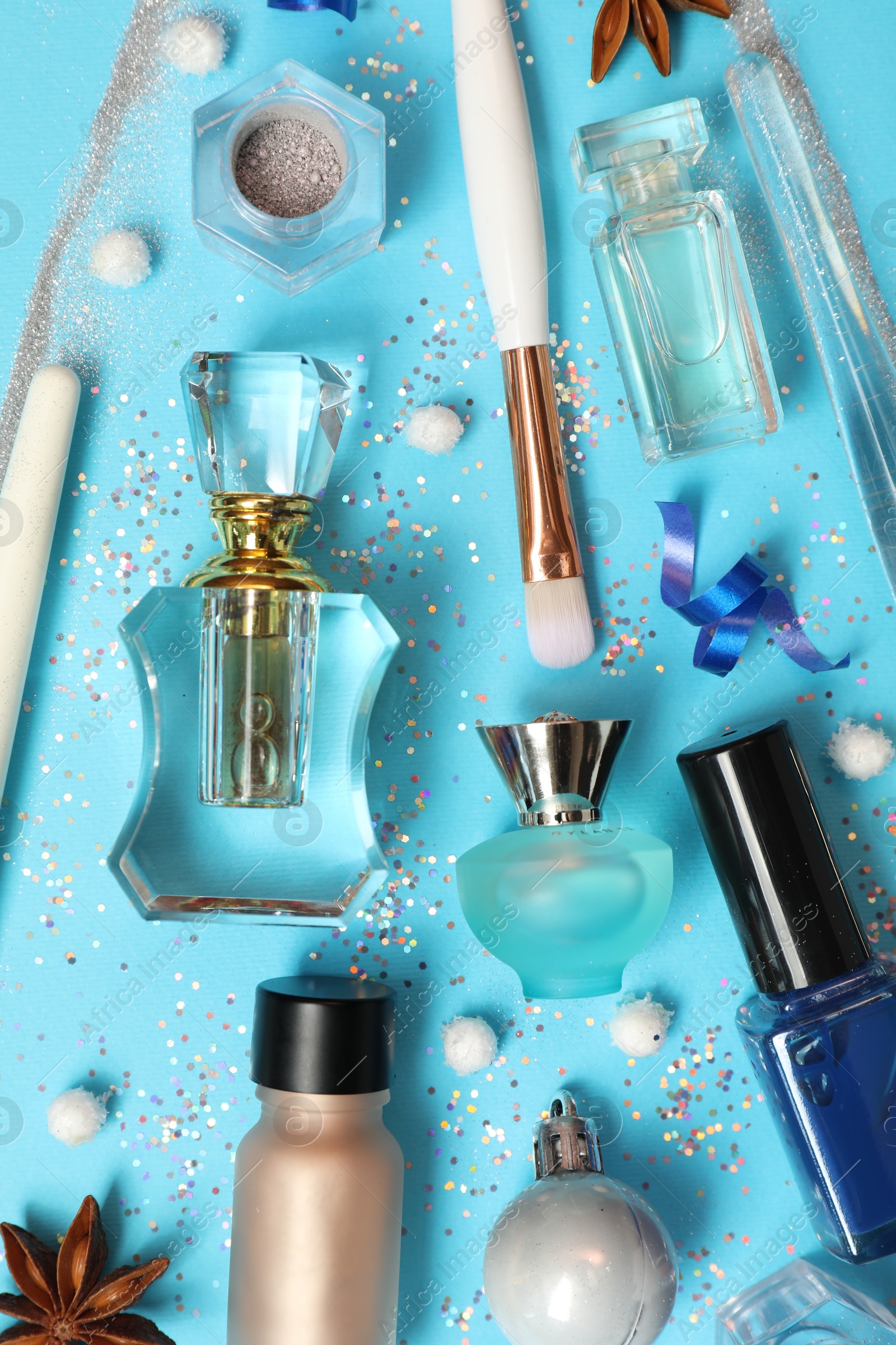 Photo of Perfume bottles and makeup products on light blue background, flat lay