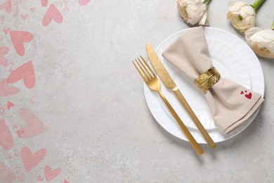 Image of Table setting for romantic Valentine's day celebration, top view. Plates, cutlery, flowers and hearts on grey table