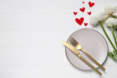 Image of Table setting for romantic Valentine's day celebration, top view. Plate, cutlery, flowers and hearts on white wooden table, space for text