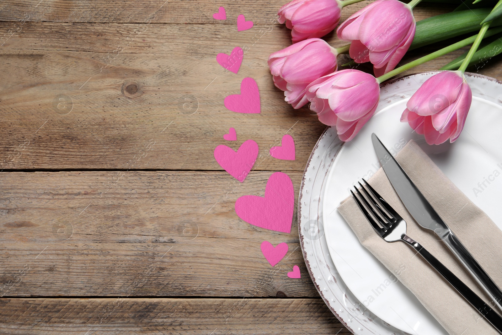 Image of Table setting for romantic Valentine's day celebration, top view. Plates, cutlery, flowers and hearts on wooden table, space for text