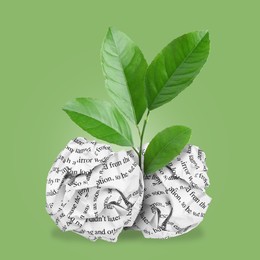 Seedling with leaves growing from crumpled paper balls on green background. Recycling