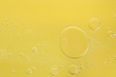 Essential oil bubbles on yellow background, macro view. Cosmetic product