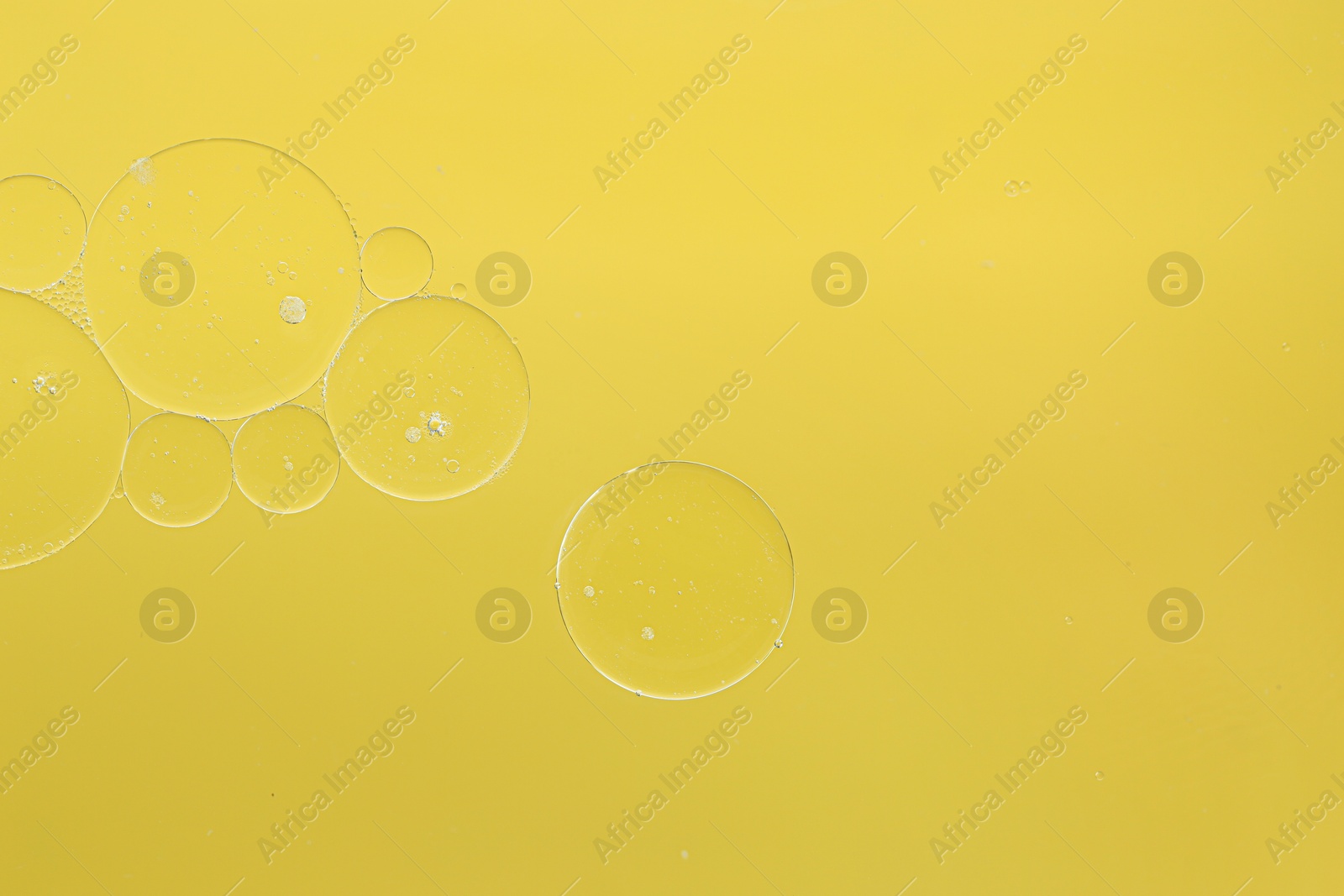 Photo of Cosmetic oil bubbles on yellow background, macro view. Space for text