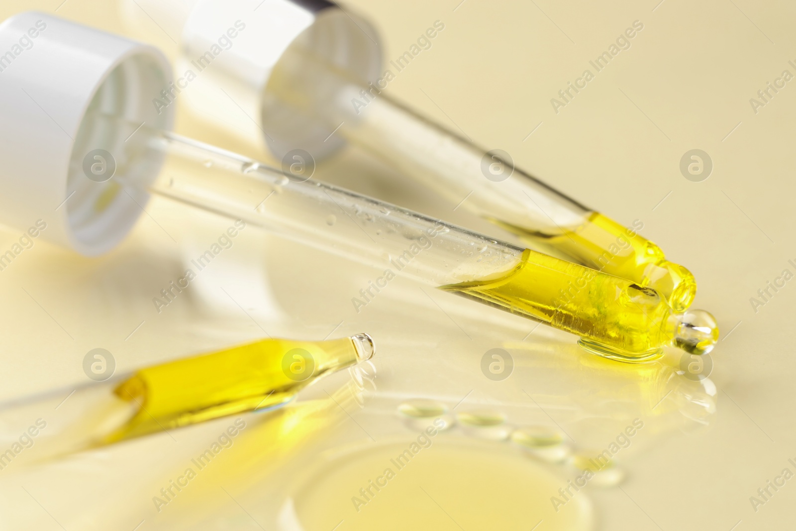 Photo of Cosmetic oil and pipettes on dark beige background, closeup