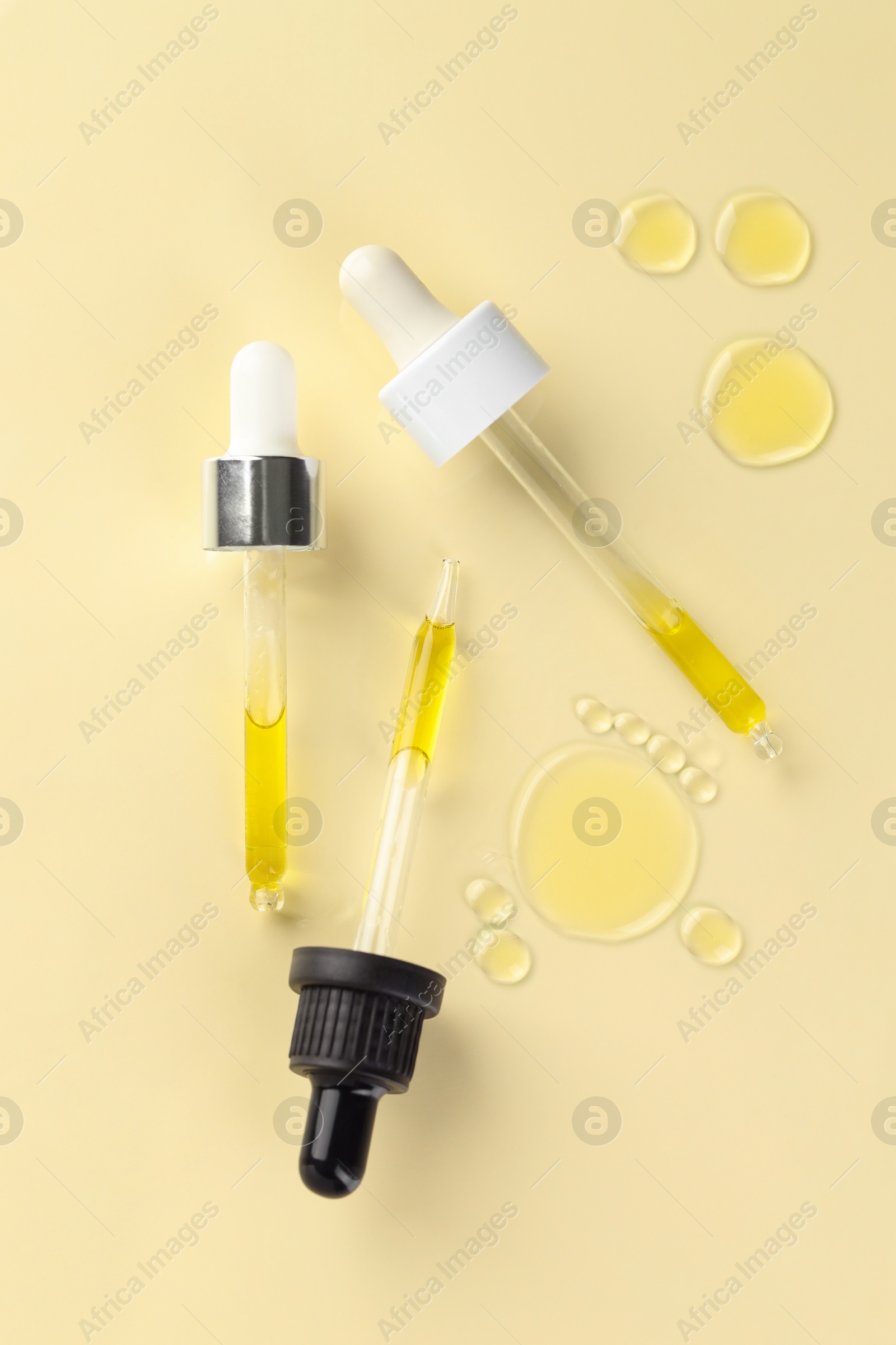 Photo of Cosmetic oil and pipettes on dark beige background, flat lay