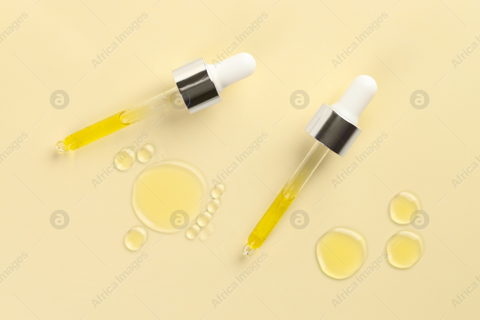 Photo of Cosmetic oil and pipettes on dark beige background, flat lay